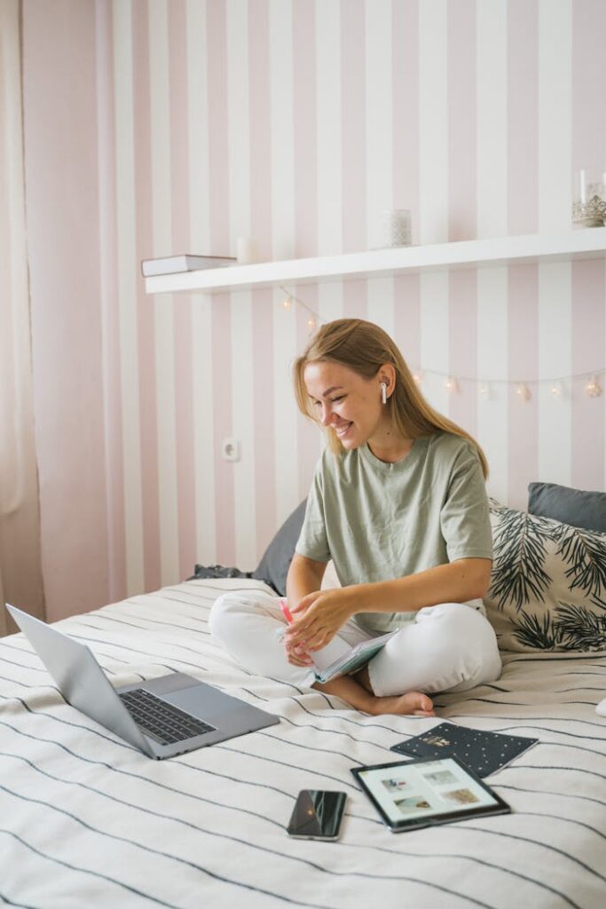 Woman enjoying an online education session while seated comfortably on her bed, using a laptop.